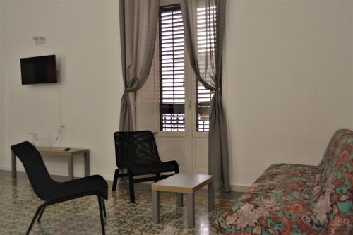 ein Wohnzimmer mit Stühlen, einem Sofa und einem Tisch in der Unterkunft Dietro al Massimo in Palermo