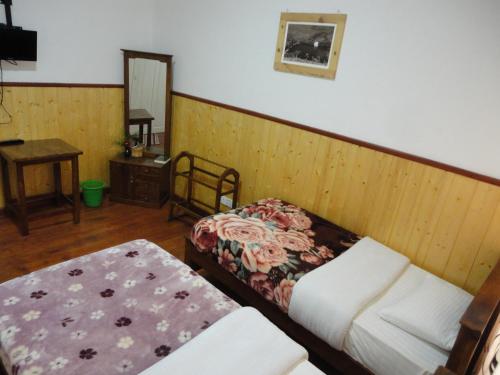 a room with two beds and a table and a mirror at Sapu's Mountain breeze Nuwara Eliya in Nuwara Eliya