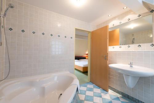a bathroom with a white tub and a sink at Hotel Eisbach in Ransbach-Baumbach