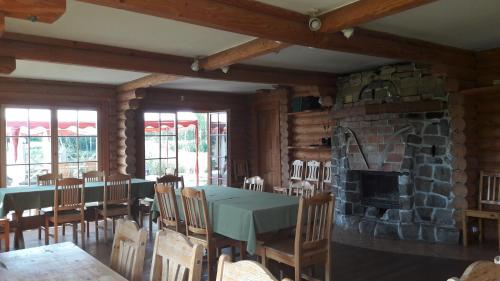 a dining room with a table and a stone fireplace at Jaun-Ieviņas in Rauna