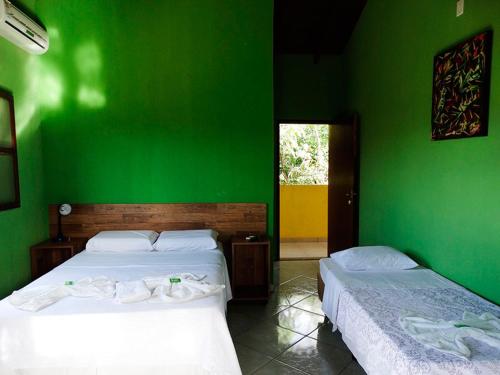 two beds in a room with green walls at Pousada Arraial Das Cores in Pirenópolis