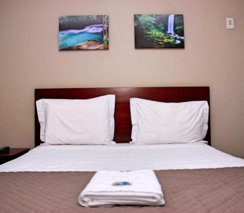 a bed with two pillows and a towel on it at Mais Hotel in Araguaína
