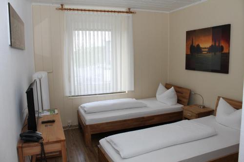 a room with two beds and a tv and a window at Hotel Rheinischer Hof in Geldern