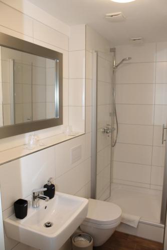 een badkamer met een toilet, een wastafel en een douche bij Hotel Rheinischer Hof in Geldern