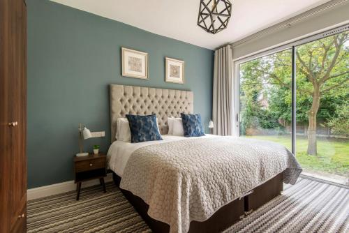 a bedroom with a large bed with blue walls and a window at M-Hotels Apartments in London