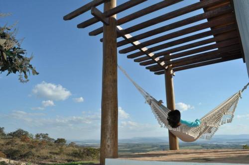 a person laying in a hammock on a house at Pousada Encantos do Cerrado in Delfinópolis