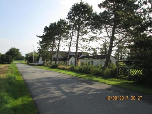 a road with a house and trees on the side at Bakkegården Homestay in Spottrup