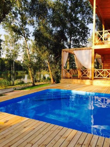 a pool with a wooden deck and a house at Relax villa Poduzska in Sinyak