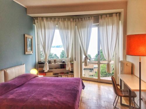 een slaapkamer met een paars bed en een groot raam bij Bella in Stresa