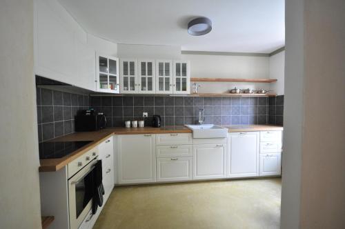 a kitchen with white cabinets and a sink at Jungfrau Family Holiday Home in Matten