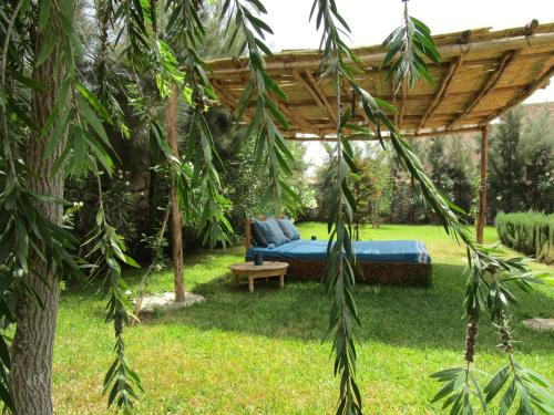 a bed in a garden with a wooden pergola at La Maison des Ailleurs in Essaouira