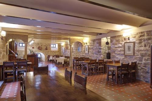 a restaurant with wooden tables and chairs and stone walls at Parador de Ubeda in Úbeda