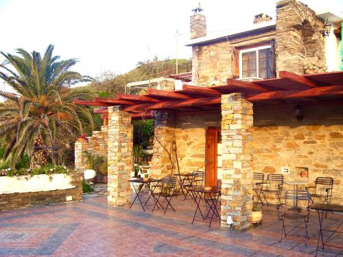 Casa de piedra con patio con mesas y sillas en Kostis Rooms, en Korissia
