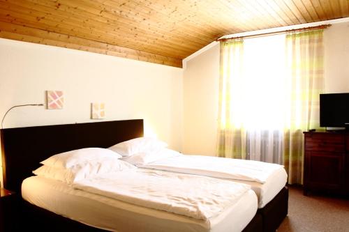 a bedroom with a bed with white sheets and a window at Bimesmeier Gasthof & Pension in Kößlarn