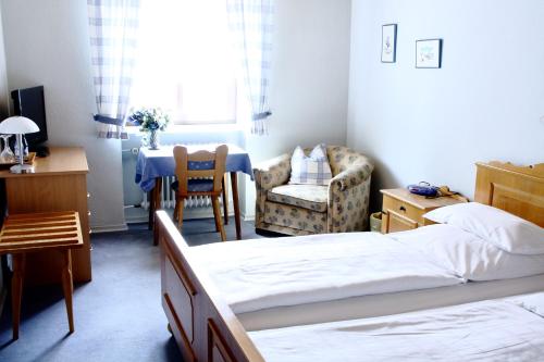 a bedroom with two beds and a chair and a table at Bimesmeier Gasthof & Pension in Kößlarn