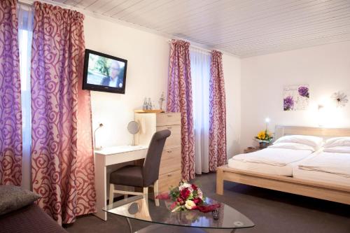 a bedroom with a bed and a desk and curtains at Bimesmeier Gasthof & Pension in Kößlarn