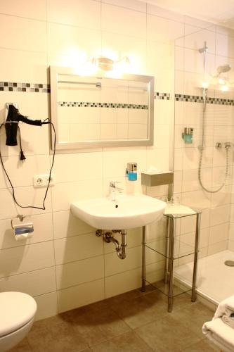 a bathroom with a sink and a shower and a toilet at Bimesmeier Gasthof & Pension in Kößlarn