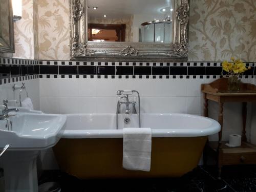a bathroom with a tub and a sink and a mirror at The Lonsdale in Blackpool