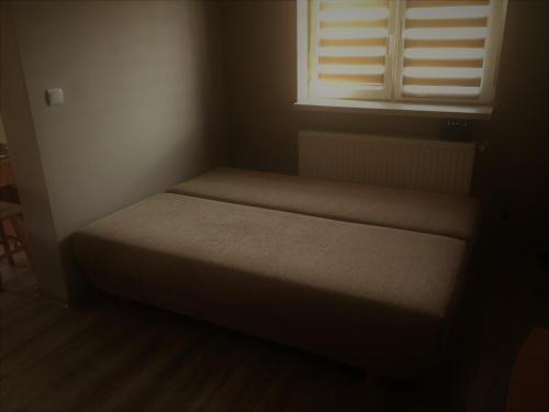 een bed in een kleine kamer met een raam bij U Dzieciola in Zwierzyniec