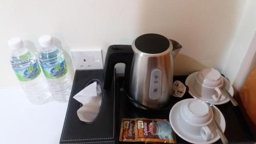 a coffee maker on a black tray next to water bottles at Pz Hotel in Kuala Kangsar