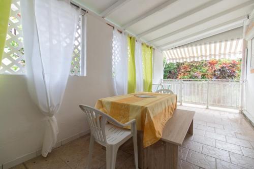 d'une salle à manger avec une table, des chaises et une fenêtre. dans l'établissement Appartement Hibiscus Martinique, au Lamentin