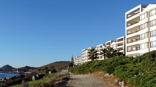 a building on a hill next to the ocean at Departamento Puerto Velero in Puerto Velero