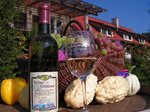 una botella de vino junto a una cesta de frutas y hortalizas en Winnica Na Leśnej Polanie, en Zabór