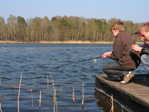 two boys on a dock fishing on a lake at Winnica Na Leśnej Polanie in Zabór