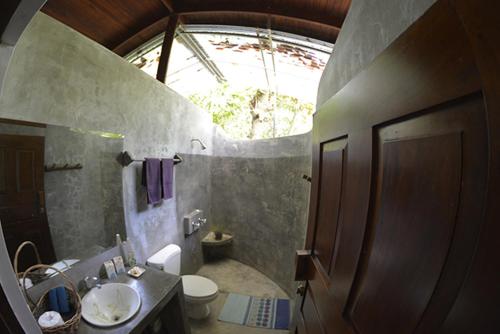 baño con lavabo y aseo y ventana en Indigo Yoga Surf Resort, en Mal País