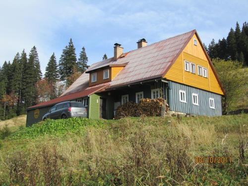 a yellow and blue house on top of a hill at Horská Chata U Básníka in Horní Malá Úpa
