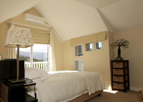 a bedroom with a white bed and a window at The Loft in Hout Bay