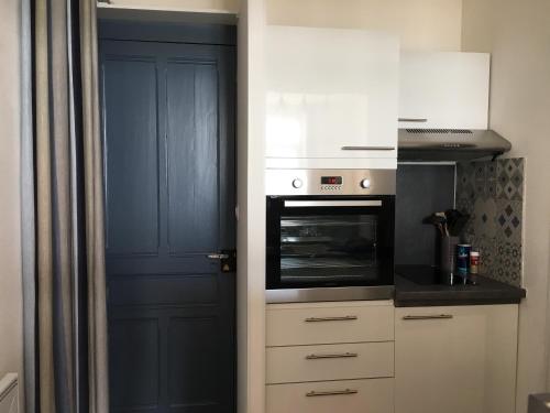 a kitchen with a oven and a blue door at Studio (Coup de Coeur) Wimereux in Wimereux