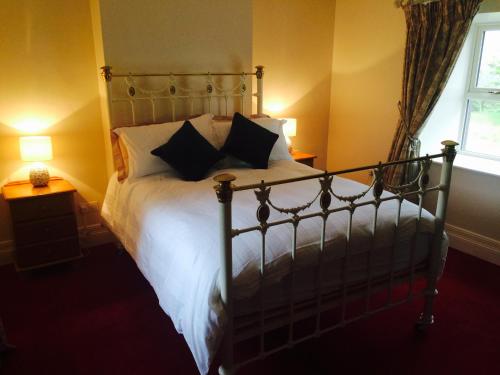 a bedroom with a bed with white sheets and pillows at Scarlett Rose Cottage in Cookstown