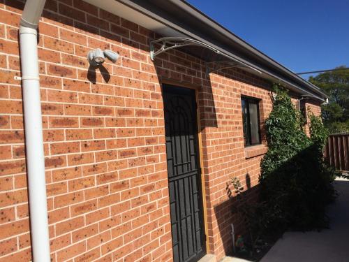 a brick house with a black door and a window at Grannyflat in Bankstown