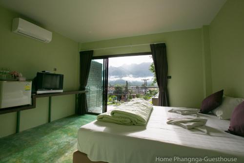 a bedroom with a large bed with a window at Home Phang-Nga Guesthouse in Phangnga