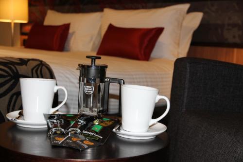 a coffee maker on a table next to two cups at Mantra Gladstone in Gladstone