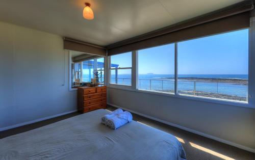 a bedroom with a bed and a view of the ocean at Stanley View Beach House in Stanley
