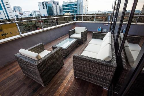 a balcony with wicker chairs and tables on a building at Rivertain Hotel in Daegu