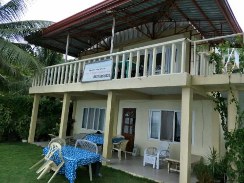 a house with a balcony with tables and chairs at Anton's Beach Resort in Oslob