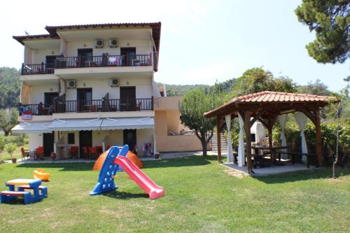 una casa con parque infantil frente a un edificio en Zisios Studios, en Vourvourou