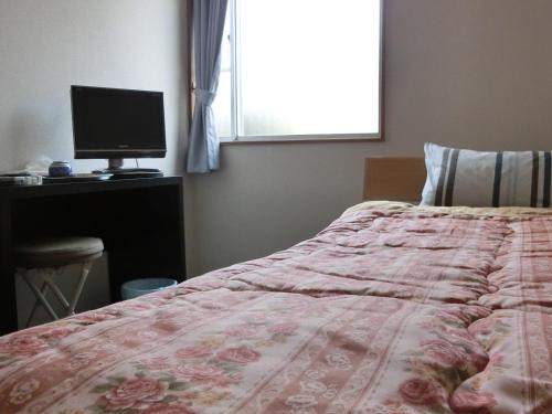 a bedroom with a bed and a computer on a desk at Suzukisou in Kyoto