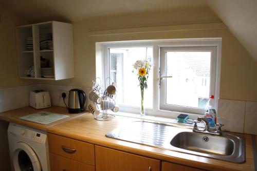 kuchnia ze zlewem i oknem w obiekcie Walkers Court By Treetop Property w mieście Cirencester