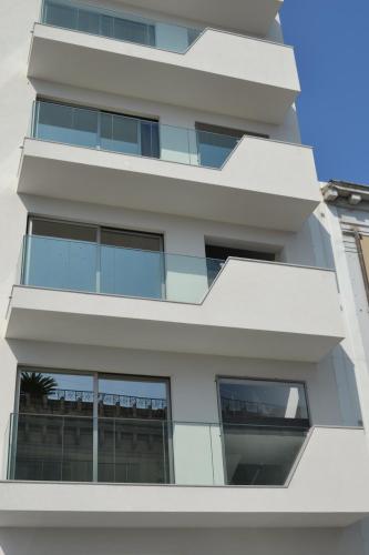 a tall white building with windows on the side at B&B Varadero in Milazzo