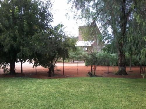 a park with trees and grass and a building at Kalahari Camelthorn Guesthouse and Camping in Askham