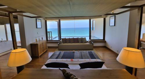 a living room with a couch and a view of the ocean at Pandanus Beach Resort & Spa in Bentota