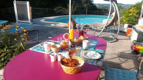- une table violette avec de la nourriture à côté d'une piscine dans l'établissement Les Haies Vives, à Choisy