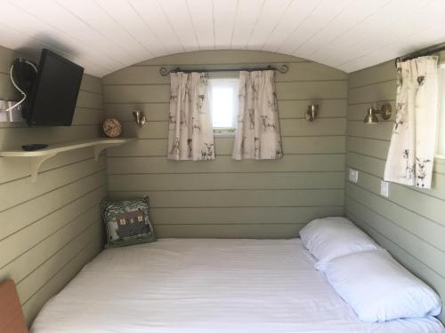 a bed in a small room with a window at Shepherd's Hut at Puttocks Farm in Great Dunmow