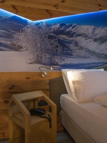 a room with a bed and a table and a picture at Hotel Amerikan in Livigno