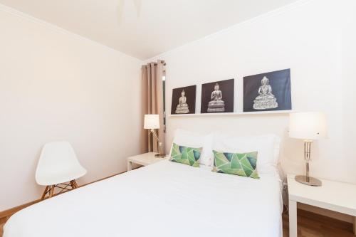 a white bedroom with a white bed and two lamps at bwelcome aroeira beach & golf in Charneca