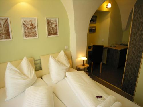 a bedroom with a bed with white pillows and a mirror at Penzion Kulíšek in Znojmo